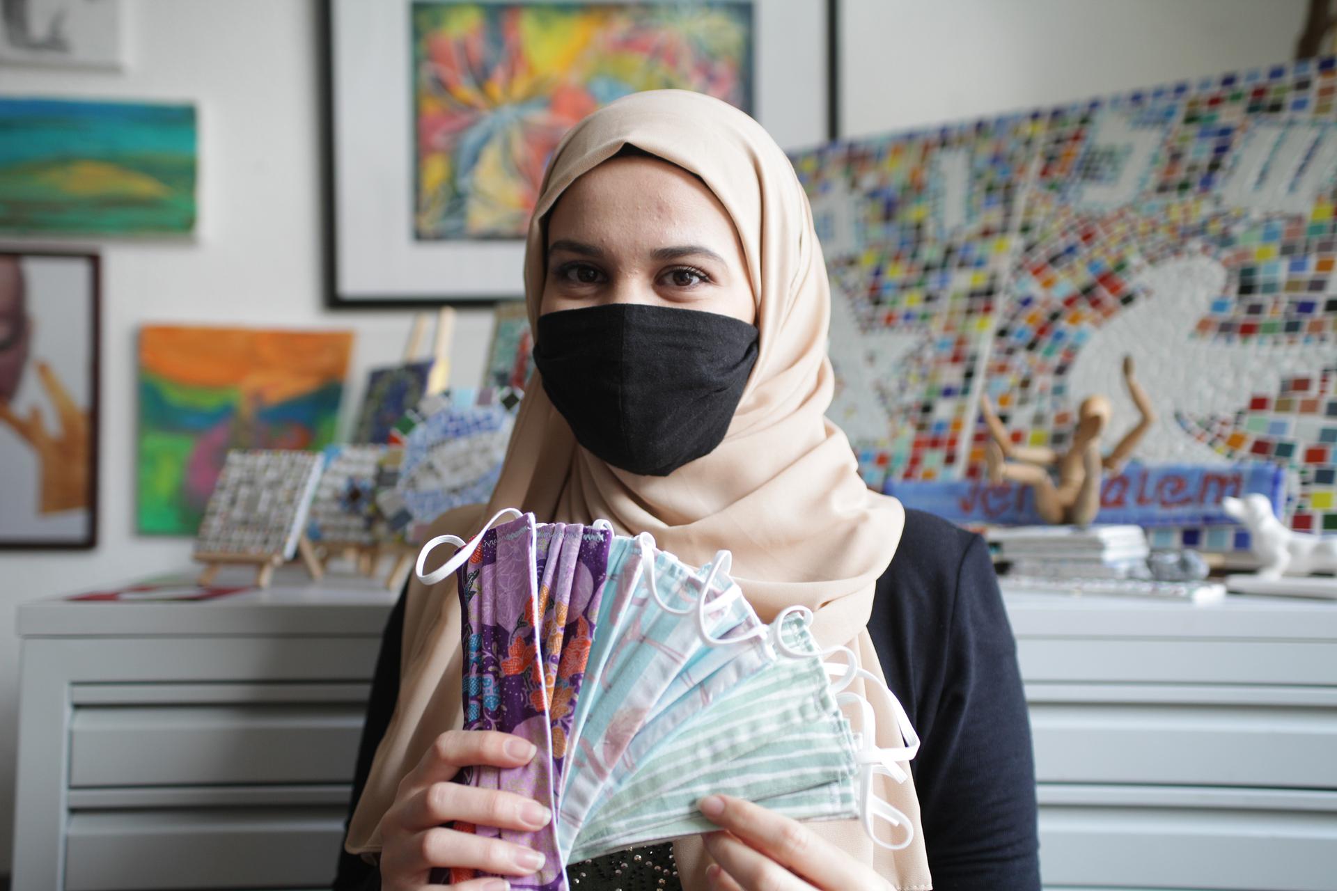 Woman in hijab holding face masks.