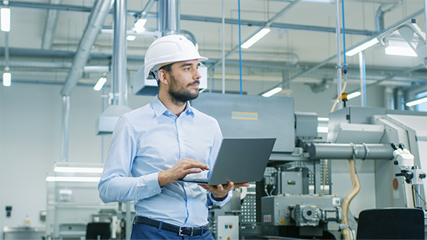 Man looking at laptop in manufacturing plant